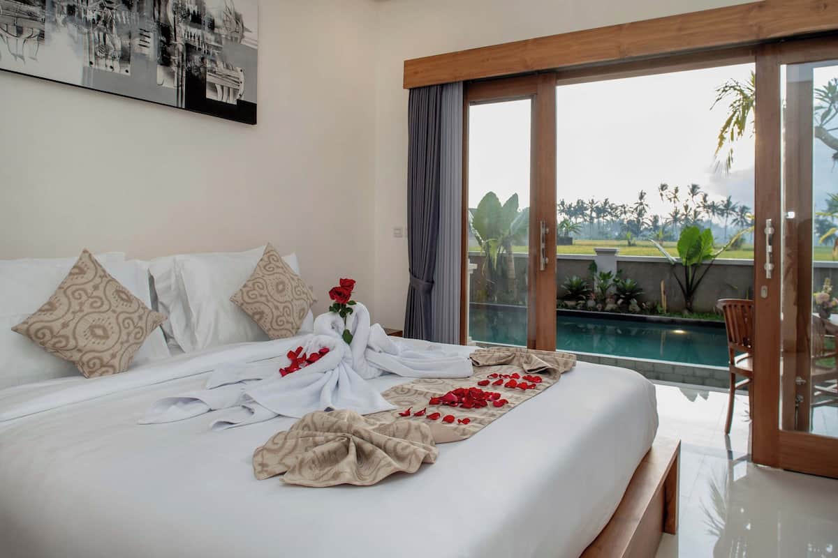 Habitación de hotel con una cama grande, vistas a una piscina y un balcón.