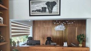 A reception desk with a framed wildlife photograph above, a wooden reception desk, a 'Cloud Nature' sign, and a plant on the right.