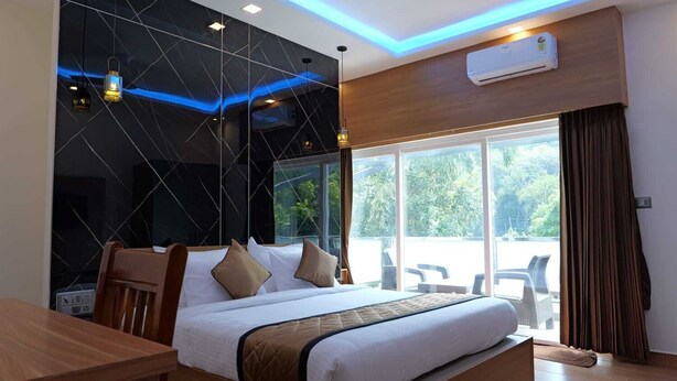 A modern hotel room with a large bed, a desk, and a view of the outdoors.