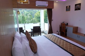 Habitación de hotel con cama, escritorio, silla y vistas a zonas verdes.