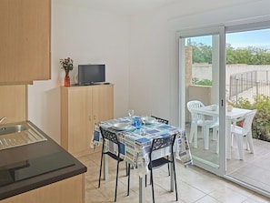 A compact kitchen with a dining area, a TV on a cabinet, and a view of the outside. - Relaxing Corsica Stay With Terrace (Linguizzetta)