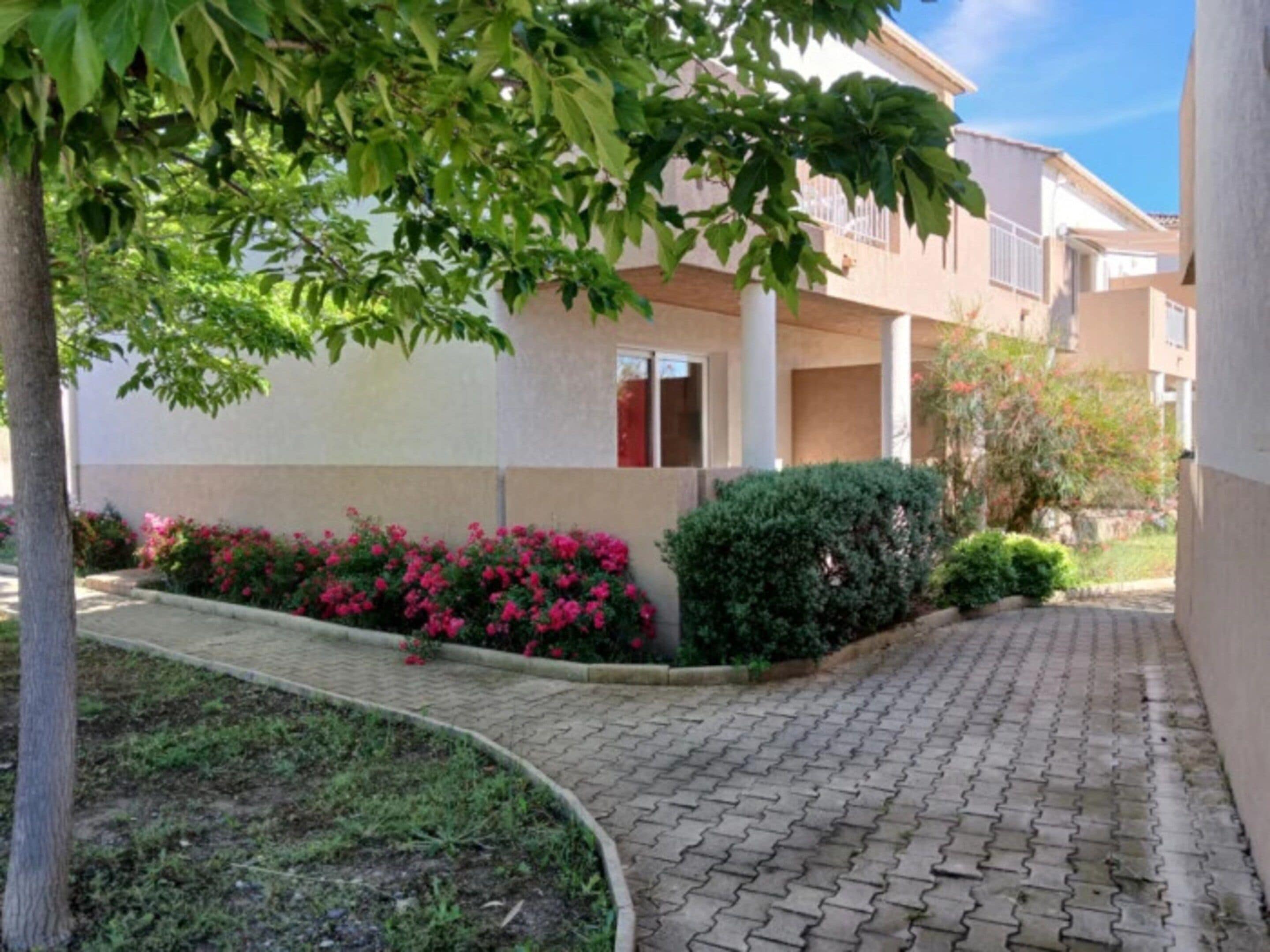 A paved walkway leading to a building with a flat roof and multiple windows.