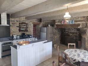 A kitchen with a stone wall, a built-in oven, a coffee machine, and a hanging light fixture.