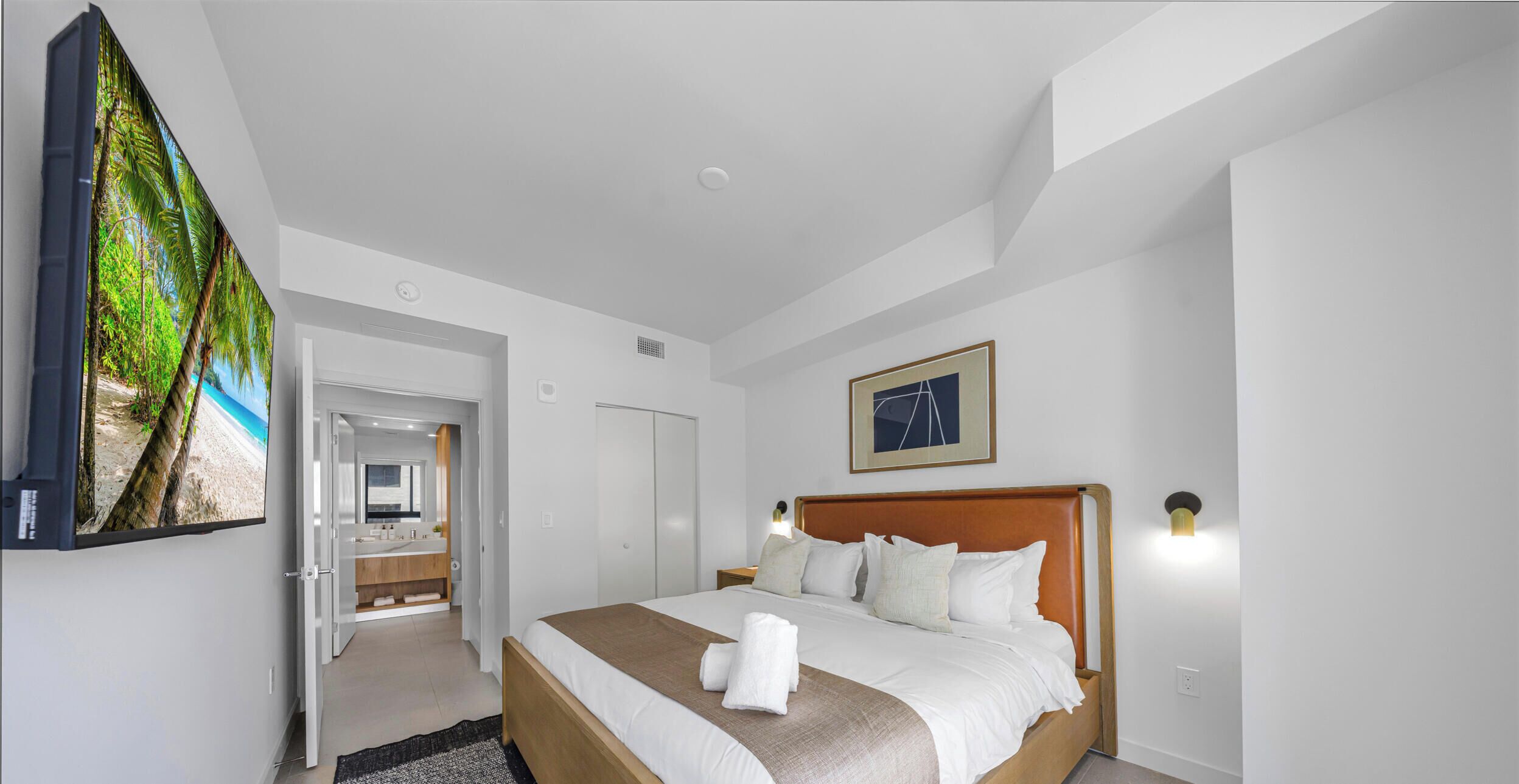Une chambre d’hôtel comprenant un lit, une télévision, une salle de bain et une porte donnant sur une autre pièce.