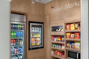 A corner store with a refrigerated beverage cooler, snack shelves, and a freezer. - Fairfield by Marriott Inn & Suites Norwalk (Norwalk)