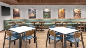 A restaurant with booths, tables, and chairs, featuring artwork on the walls and a wooden ceiling. - Fairfield by Marriott Inn & Suites Norwalk (Norwalk)