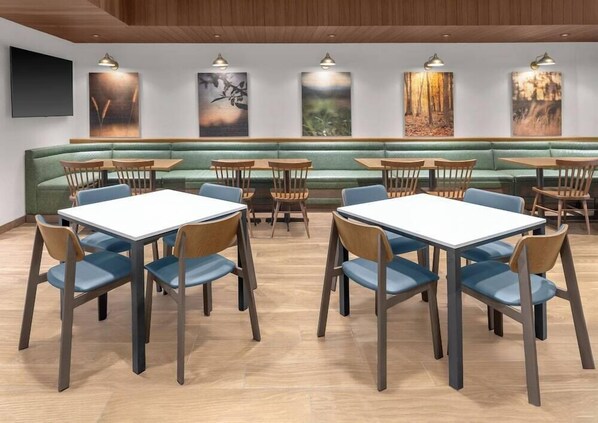Un restaurante con cabinas, mesas y sillas, con obras de arte en las paredes y techo de madera.
