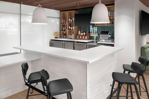 Una cocina moderna con barra, taburetes y un televisor de pantalla plana montado en la pared.