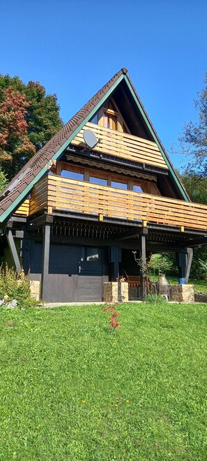 Una casa de dos plantas con techo inclinado, ático visible y puerta de garaje en la fachada.