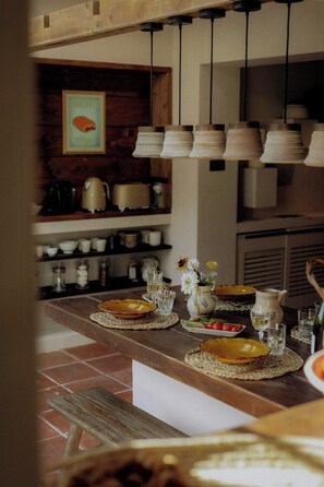 Une cuisine avec un plan de travail en bois, des casseroles suspendues et un sol carrelé.