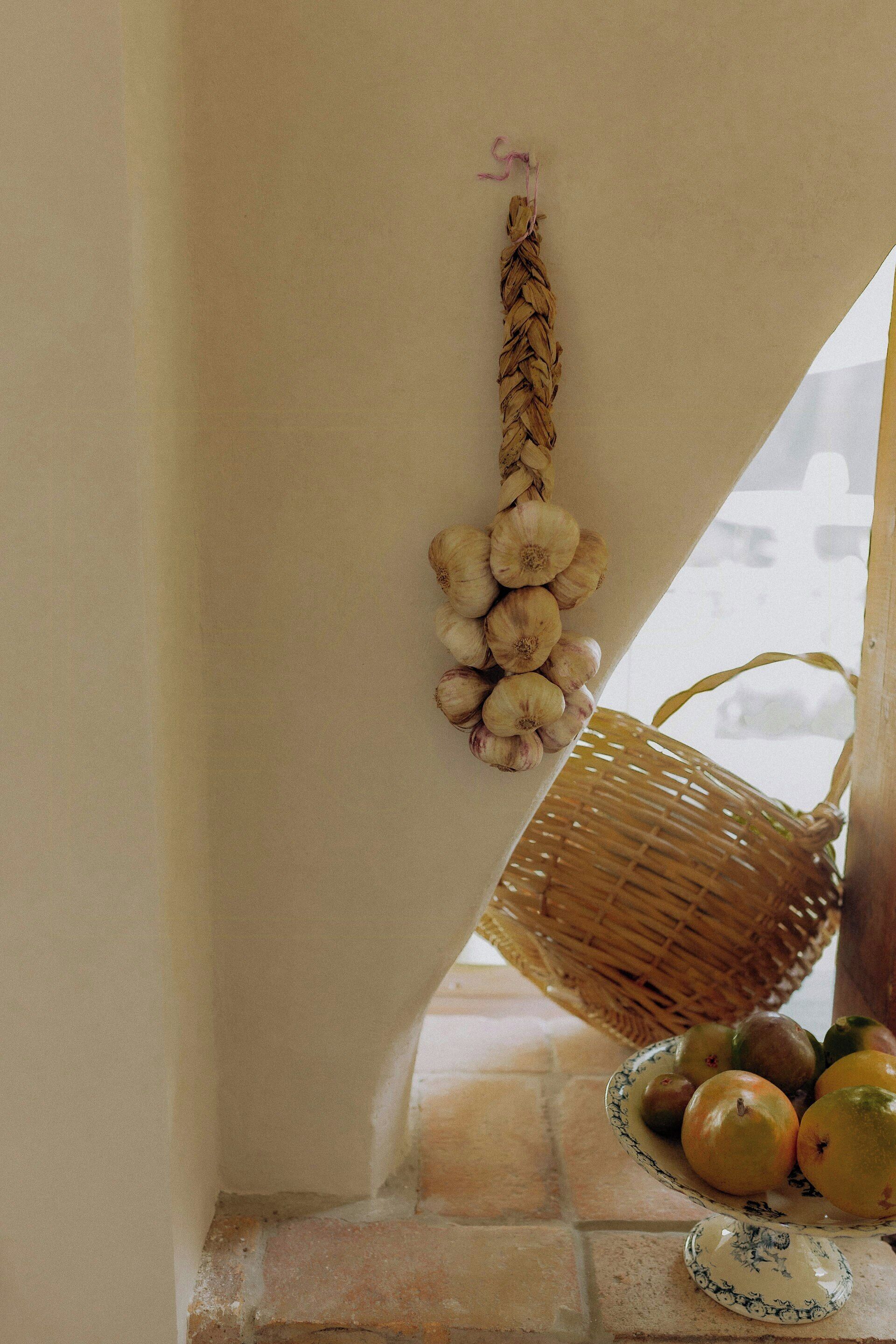 Un rincón de una habitación con una cesta tejida colgada en la pared, un plato con frutas y una cesta de mimbre en el suelo.