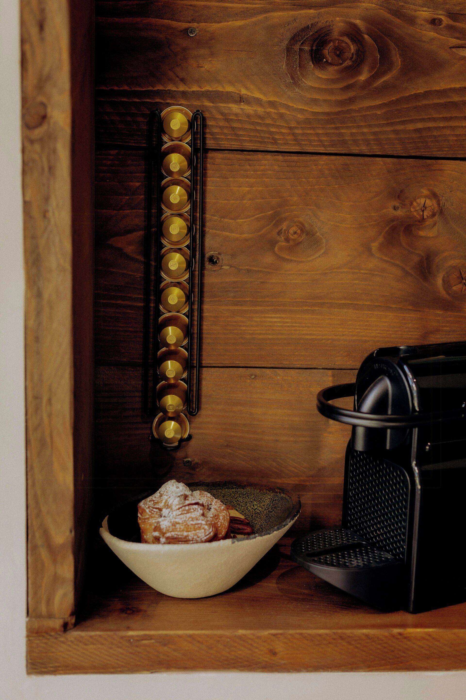 A wooden cabinet with a coffee maker and a bowl of pastries.