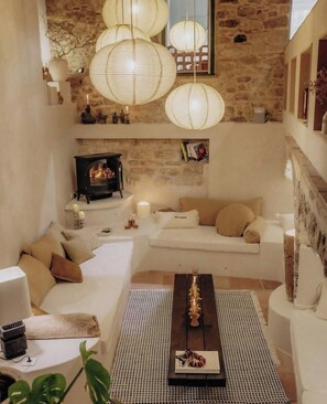 Un intérieur chaleureux avec un mur en pierre, une cheminée, un canapé blanc et des lanternes en papier suspendues.