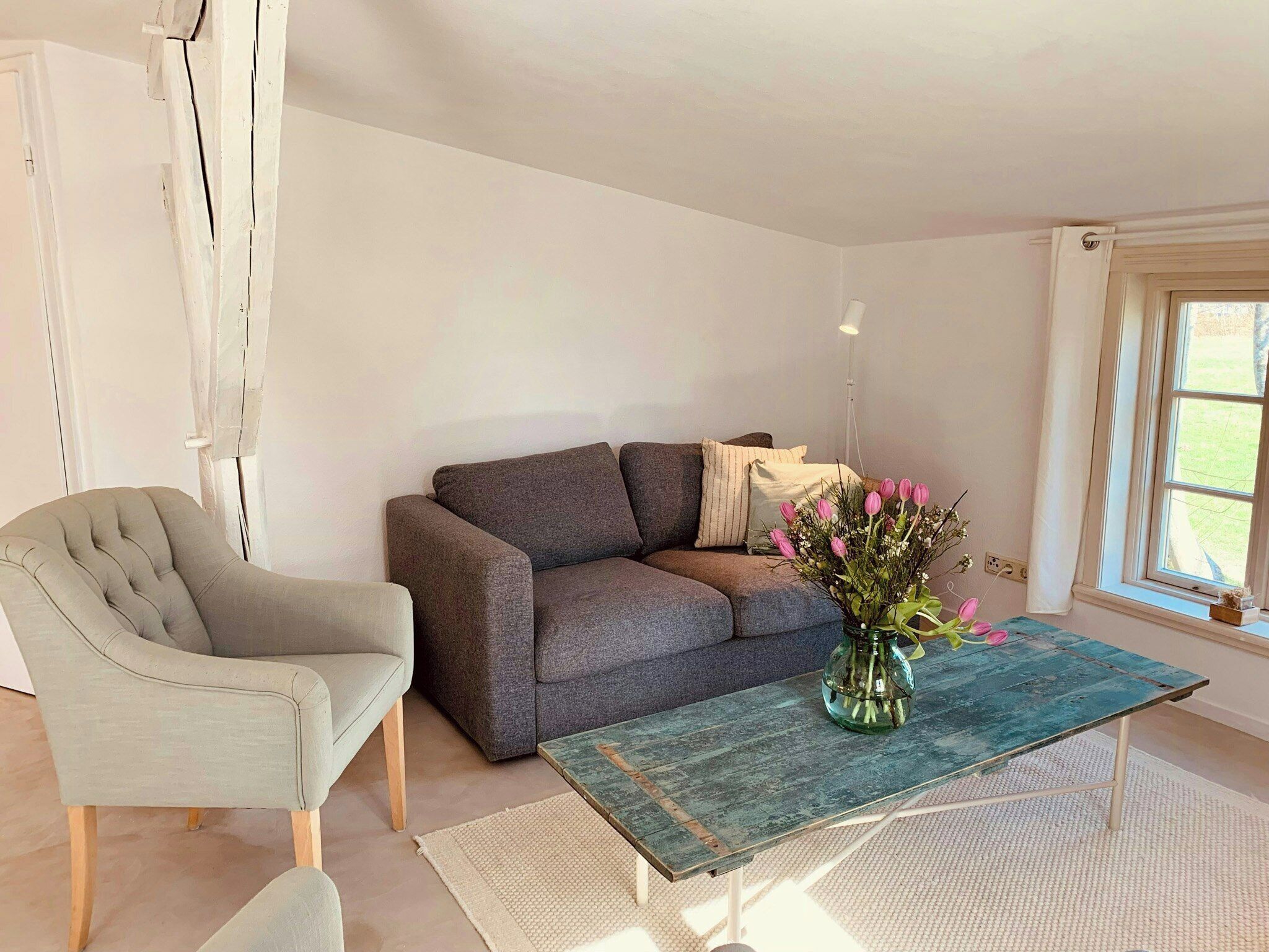 Un salon comprenant un canapé, un fauteuil et une table basse ornée d’un vase de fleurs.