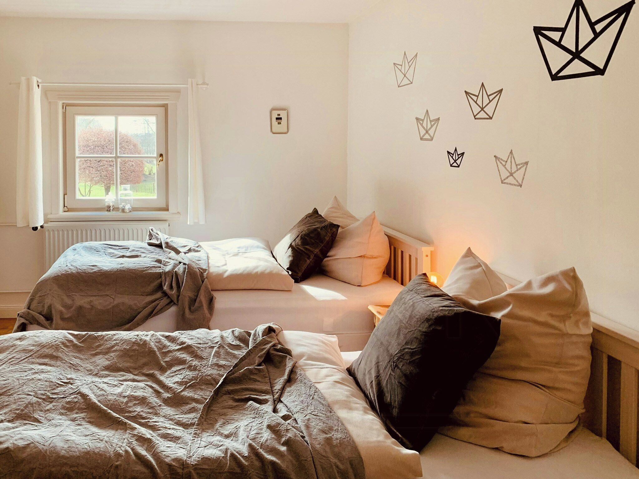 A bedroom with two beds, a window, and wall decorations.