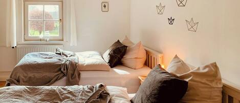 A bedroom with two beds, a window, and wall decorations.