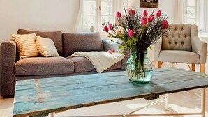 En stue med en sofa, en lænestol, et sofabord og en vase med blomster.