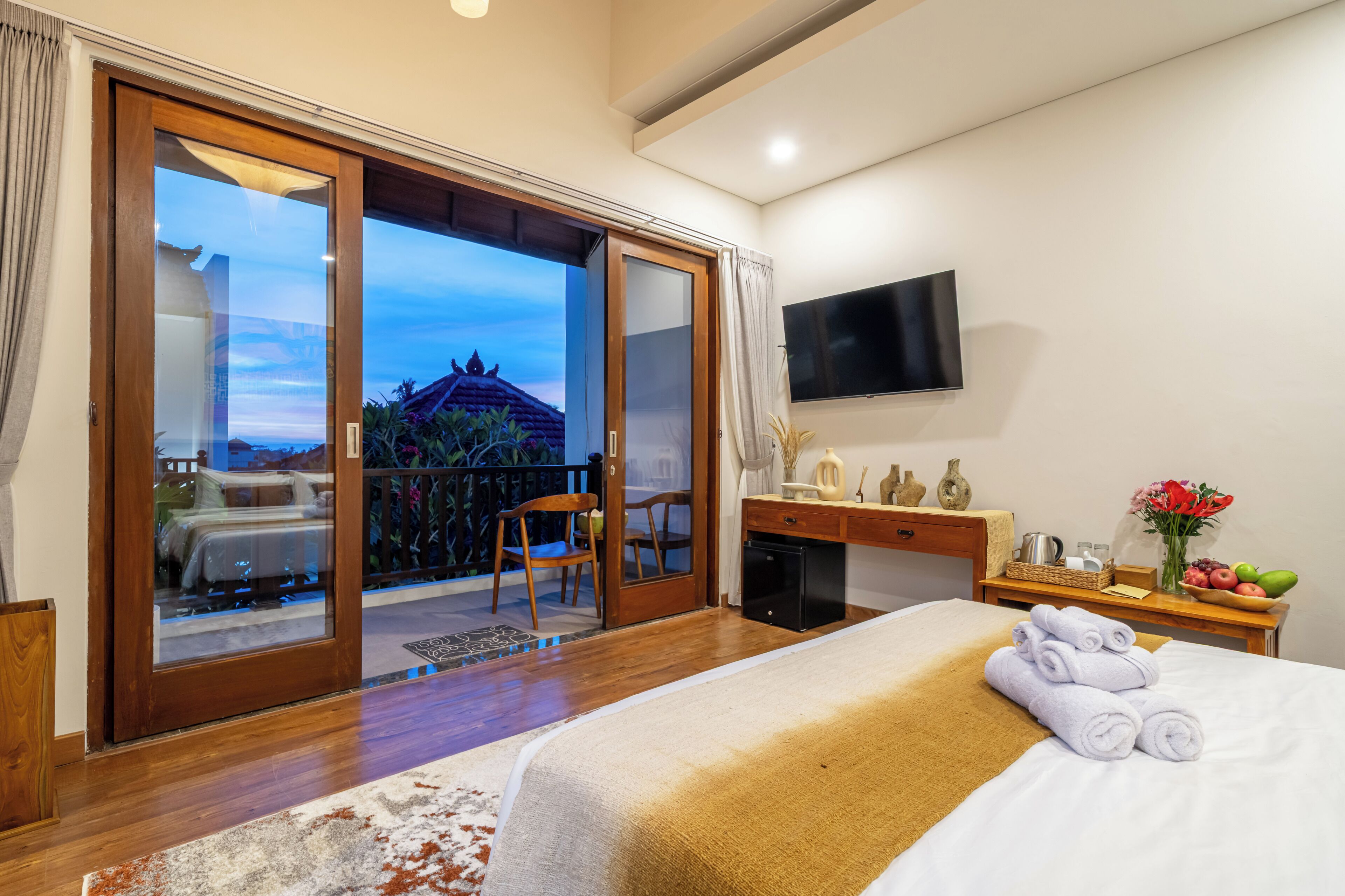 Ein Hotelzimmer mit Bett, Schreibtisch, Fernseher, einem Balkon mit Aussicht und einer kleinen Küchenzeile.