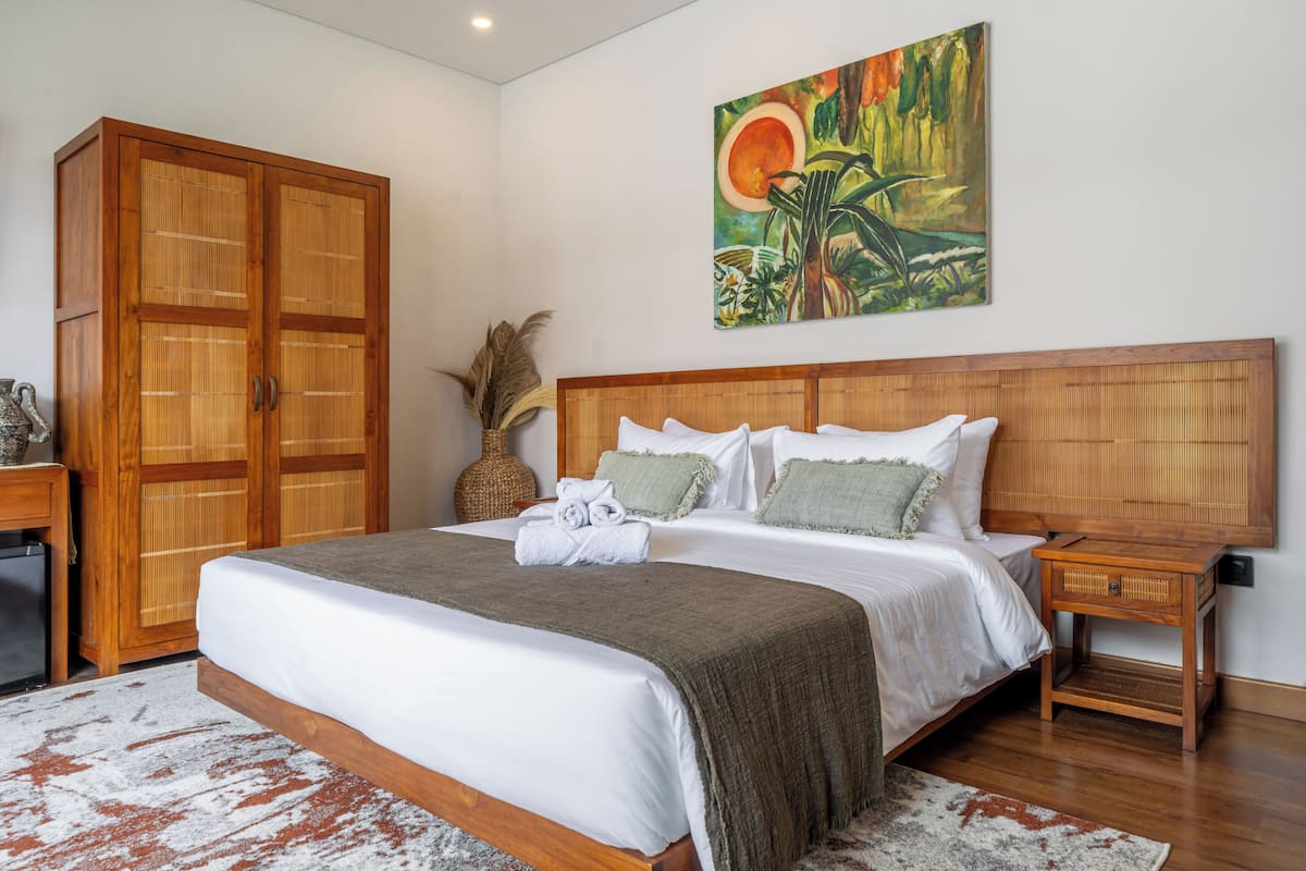 Ein Schlafzimmer mit einem großen Bett, einem Holzschrank und einem Bild an der Wand.