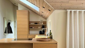 Una cocina moderna con muebles de madera, una isla central con taburetes y un ventanal sobre el fregadero.
