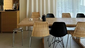 Un comedor moderno con techo de madera, una mesa grande, sillas de mimbre y una lámpara colgante.