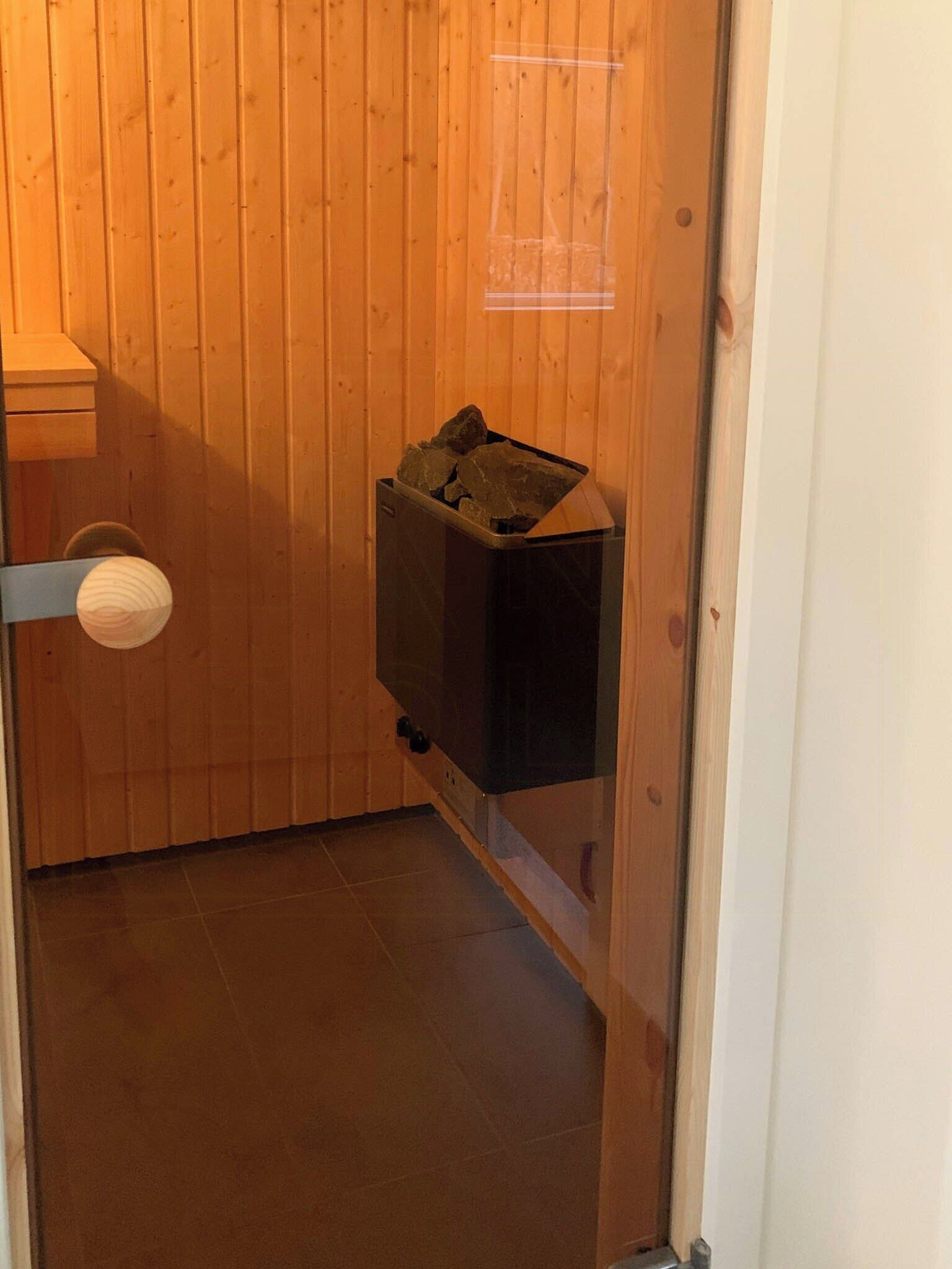 Ein Zimmer mit Holzverkleidung, einem schwarzen Mülleimer und einem weißen Türgriff.