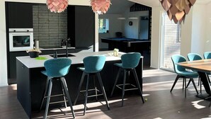 Une cuisine moderne dotée d’un îlot central, de tabourets de bar et de luminaires suspendus.