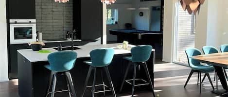 A modern kitchen with a central island, bar stools, and pendant lights.