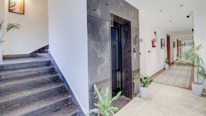 Un moderno vestíbulo de hotel con una escalera de mármol, un mostrador de recepción y plantas en macetas.