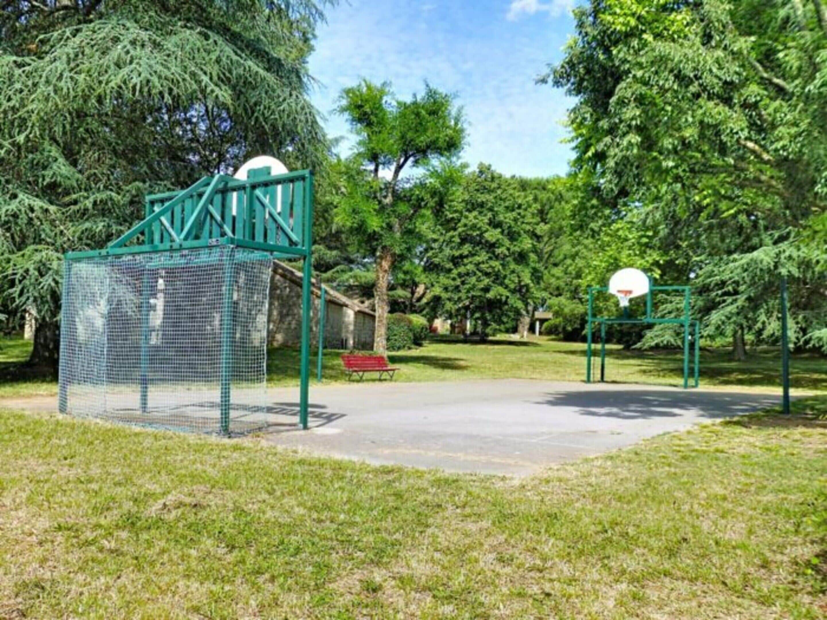 A playground with a basketball hoop and a netted climbing structure.