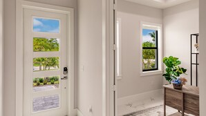 Um corredor com uma porta branca, uma janela com vista para o verde e um console de madeira com uma planta.