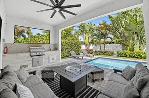 A modern outdoor living space with a pool, seating area, and a barbecue setup. - Naples Park Stay • Pool + Outdoor Kitchen + Near Vanderbilt Beach | Coastal Sol (Naples)