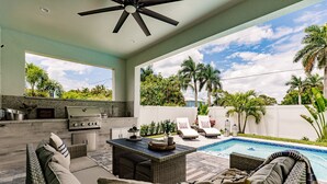 Um pátio externo com piscina, área de estar e churrasqueira.