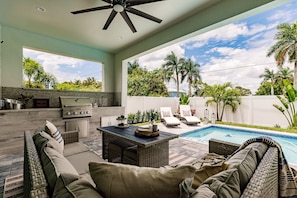 Un patio al aire libre con piscina, zona de estar y parrilla.