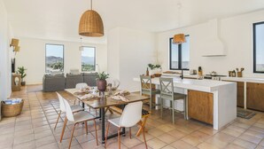 Una cucina moderna con isola centrale, zona pranzo con sedie e un divano.