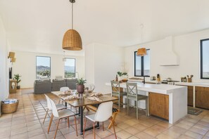Eine moderne Küche mit Kochinsel, Essbereich mit Stühlen und einer Couch.