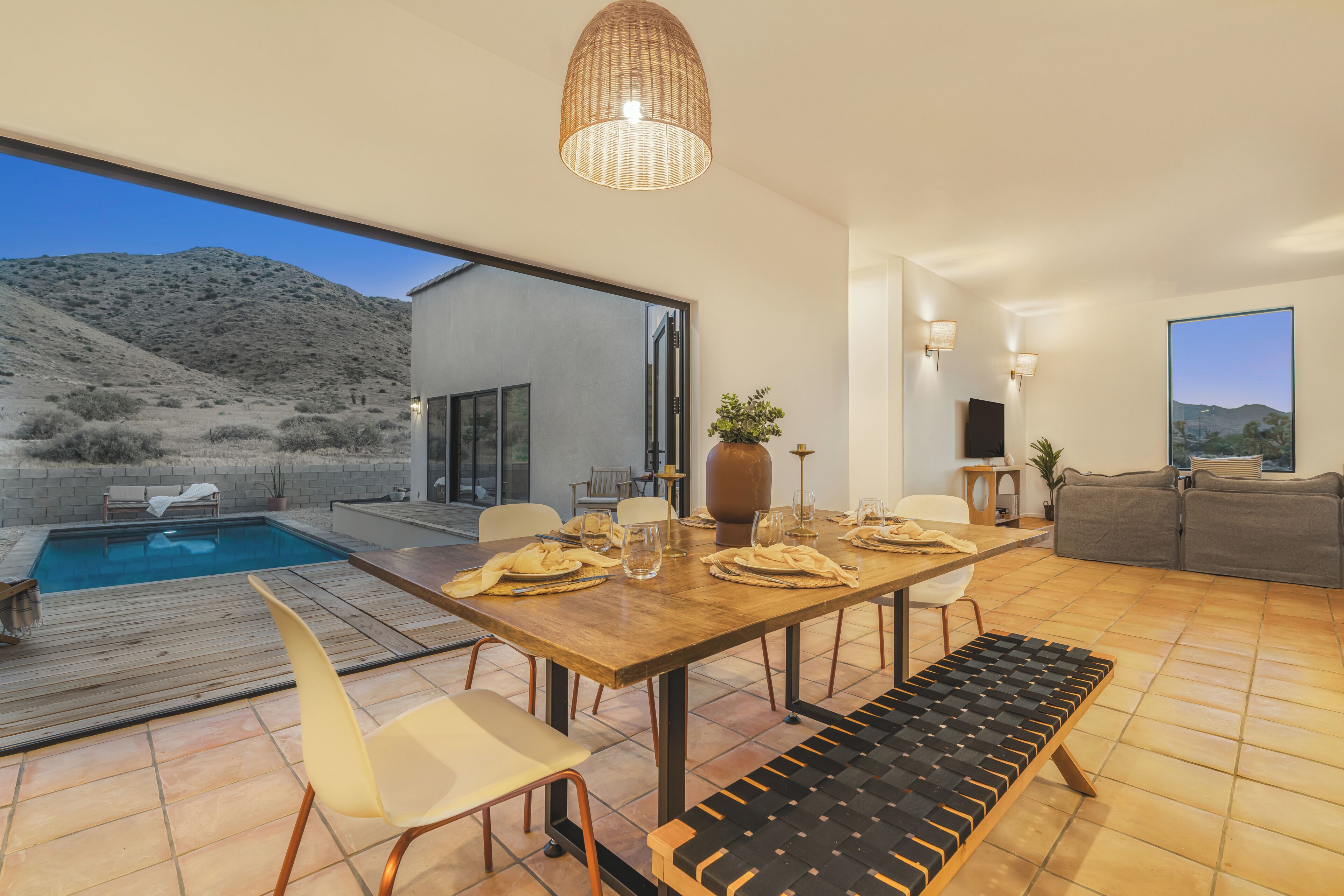Una sala de estar moderna con comedor, piscina y vistas a un paisaje montañoso.