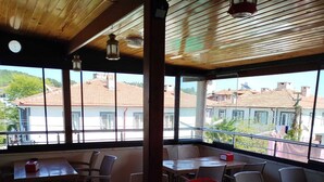 Un comedor interior con techo de madera y ventanas amplias, mesas y sillas.