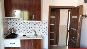 Una cocina con armarios de madera, salpicadero de azulejos, un lavabo, una estufa y una silla roja.
