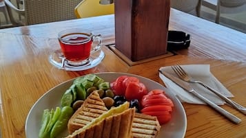 Puisesta pöydästä löytyy lautanen ruokaa, lasi punaista juomaa ja ruokailuvälineet.
