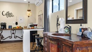 Una cocina con barra para café, taburetes, un lavabo y un espejo grande.