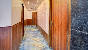 A hallway with wooden doors, a marble-patterned floor, and recessed lighting. - Townhouse Oak Panki Panchmukhi Hanuman (Kanpur)