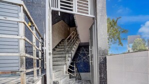 A staircase leading to a building entrance with a metal railing and a view of the sky. - Townhouse Oak Panki Panchmukhi Hanuman (Kanpur)
