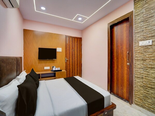 Une chambre d’hôtel avec un lit, un téléviseur fixé au mur, une armoire en bois et un mur en pierre.