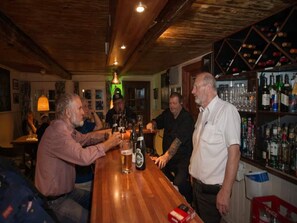 Eine Bar mit Holzbalken, einer Theke und Regalen mit Flaschen.