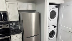 Een functionele keuken met een roestvrijstalen koelkast, een magnetron, een oven, en een ingebouwde wasmachine en droger.