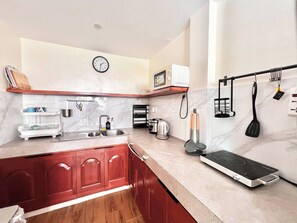 A kitchen with a sink, stove, microwave, and a clock on the wall.