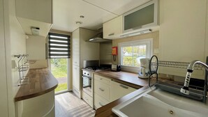 Uma cozinha compacta com fogão a gás, torradeira e cafeteira, pia com torneira e janela que traz luz natural.