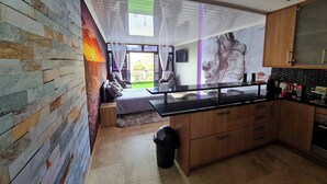 A modern kitchen with a central island, wooden cabinets, and a view of the outdoors. - Waterfront Deco apartment 2 sleeper lake views (Cape Town)