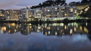 Un hotel sul lungomare con diversi piani, balconi e il suo riflesso nell'acqua.